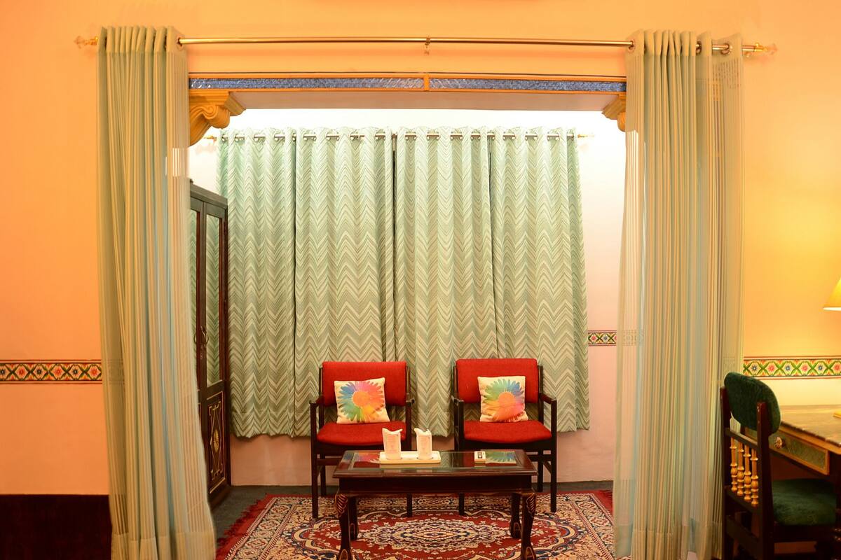 Una habitación con dos sillas rojas, una mesita y una lámpara.