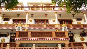 Um edifício de vários andares com detalhes arquitetônicos elaborados, incluindo colunas, padrões decorativos e varandas.