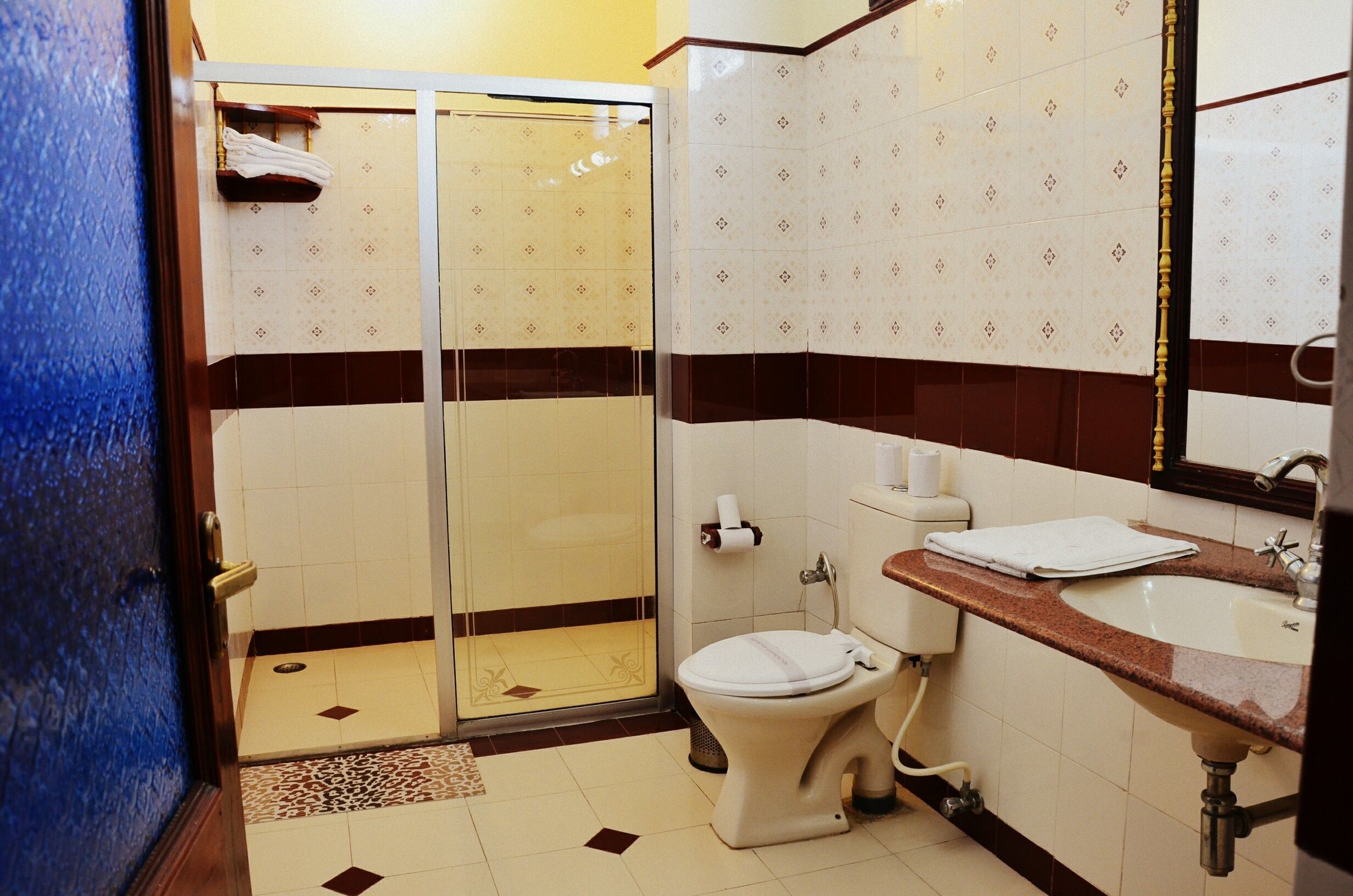 A bathroom with a shower, toilet, sink, and mirror.
