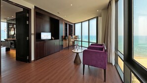 A spacious room with a wooden floor, a television, a round table, and a purple chair.