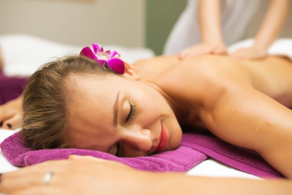 A person receiving a massage on a bed with a purple towel.