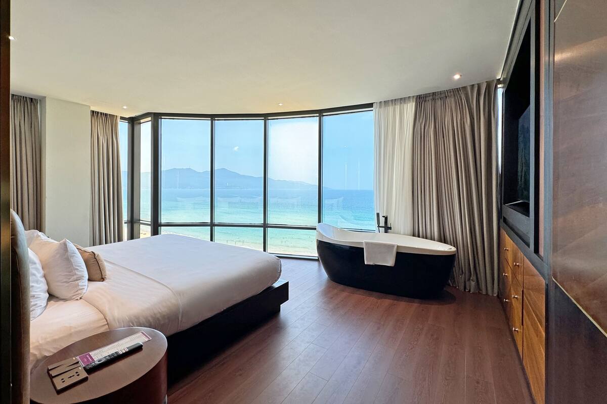 Une chambre d’hôtel moderne avec un grand lit, une baignoire et un téléviseur.