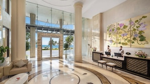 A hotel lobby with a reception desk, seating area, and a large window overlooking the outdoors.