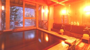 Een houten spa met een groot binnenzwembad, houten banken en een sauna.