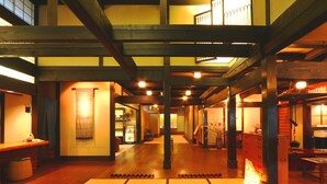 Een traditioneel Japans hotel met tatami vloermatten, houten balken en warme verlichting.