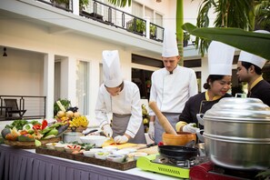 A chef preparing food in a kitchen with a variety of fresh ingredients and cooking utensils. - Diamond D'Angkor Boutique (Siem Reap)