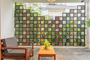 A room with a wooden chair, a small wooden table with a plant, and a decorative partition with a geometric pattern. - Diamond D'Angkor Boutique (Siem Reap)