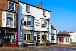 Un pub tradicional llamado "The White Horse", con fachada clásica, ventanas amplias y una cartelera.