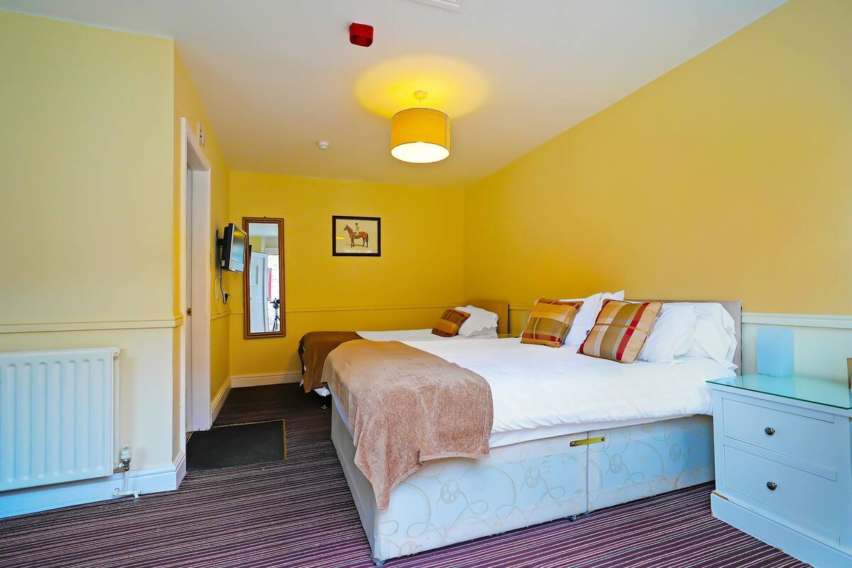 A hotel room with a bed, bedside table, and a mirror.