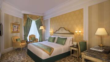 A hotel room with a large bed, two chairs, a desk, and a nightstand.