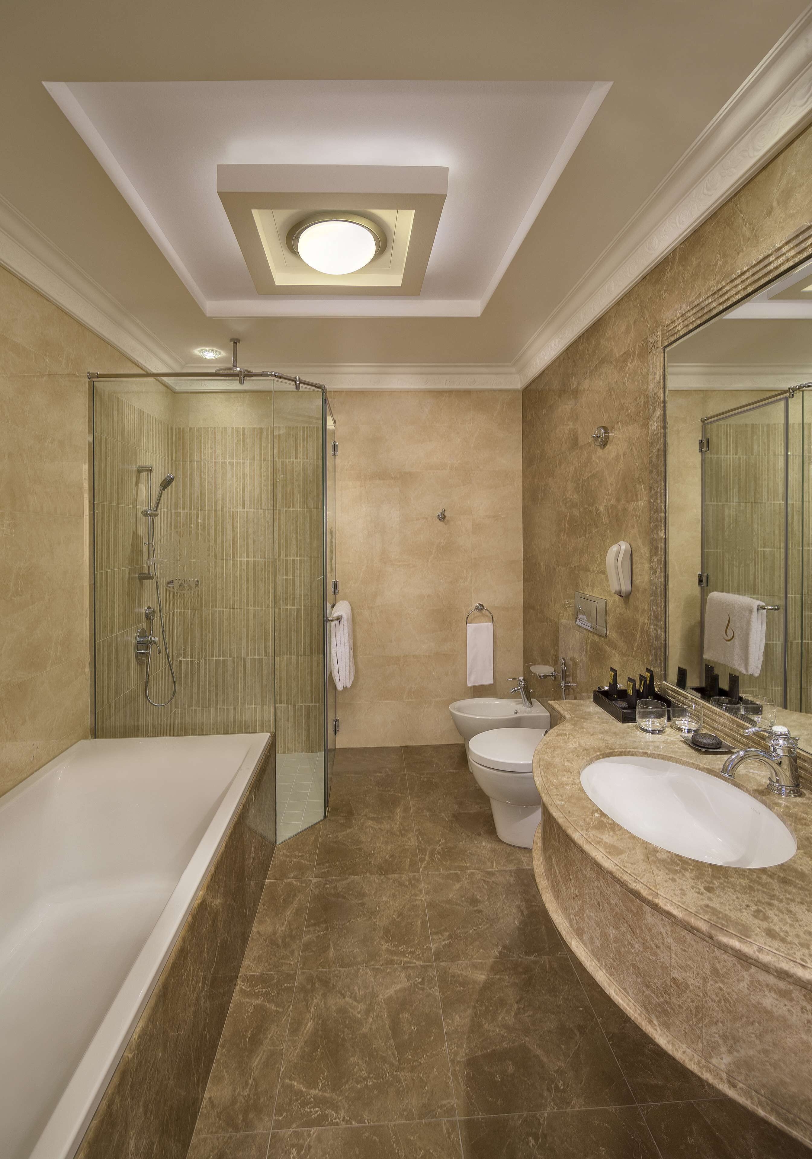 Een moderne badkamer met een douchecabine van glas, een vrijstaand bad, een wastafel met grote spiegel en een toilet.