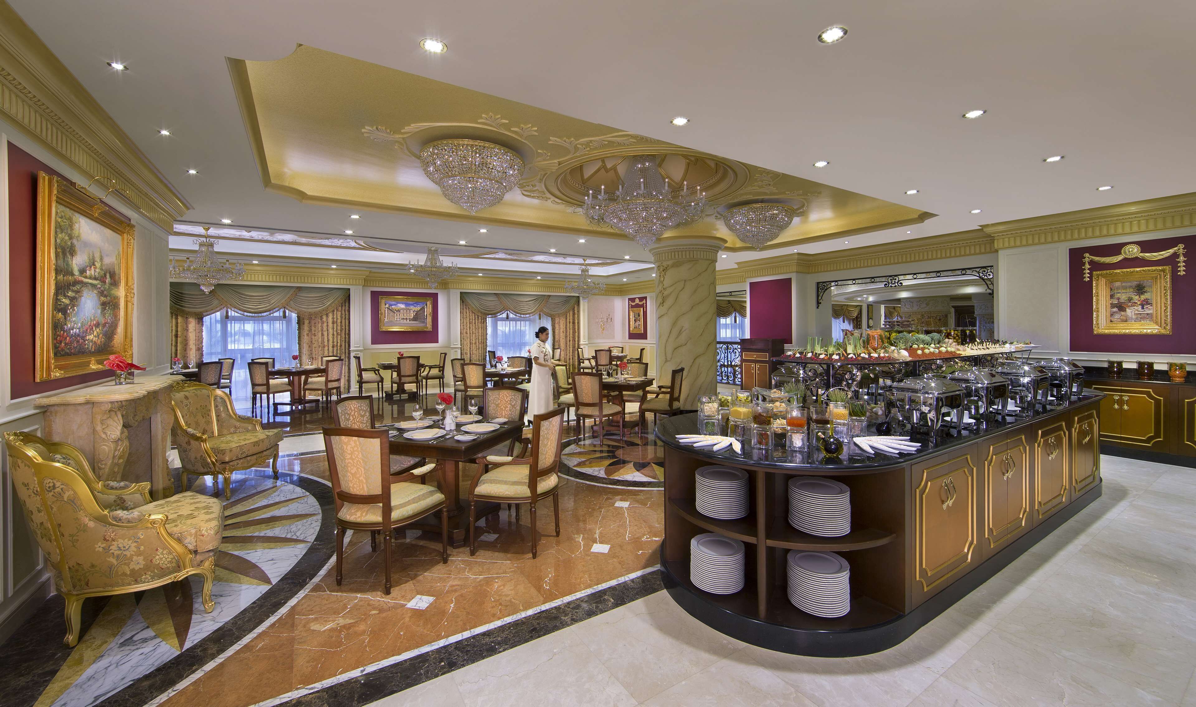 Um hall de hotel luxuoso com lustres elaborados, área de bar central e arranjos de assentos elegantes.