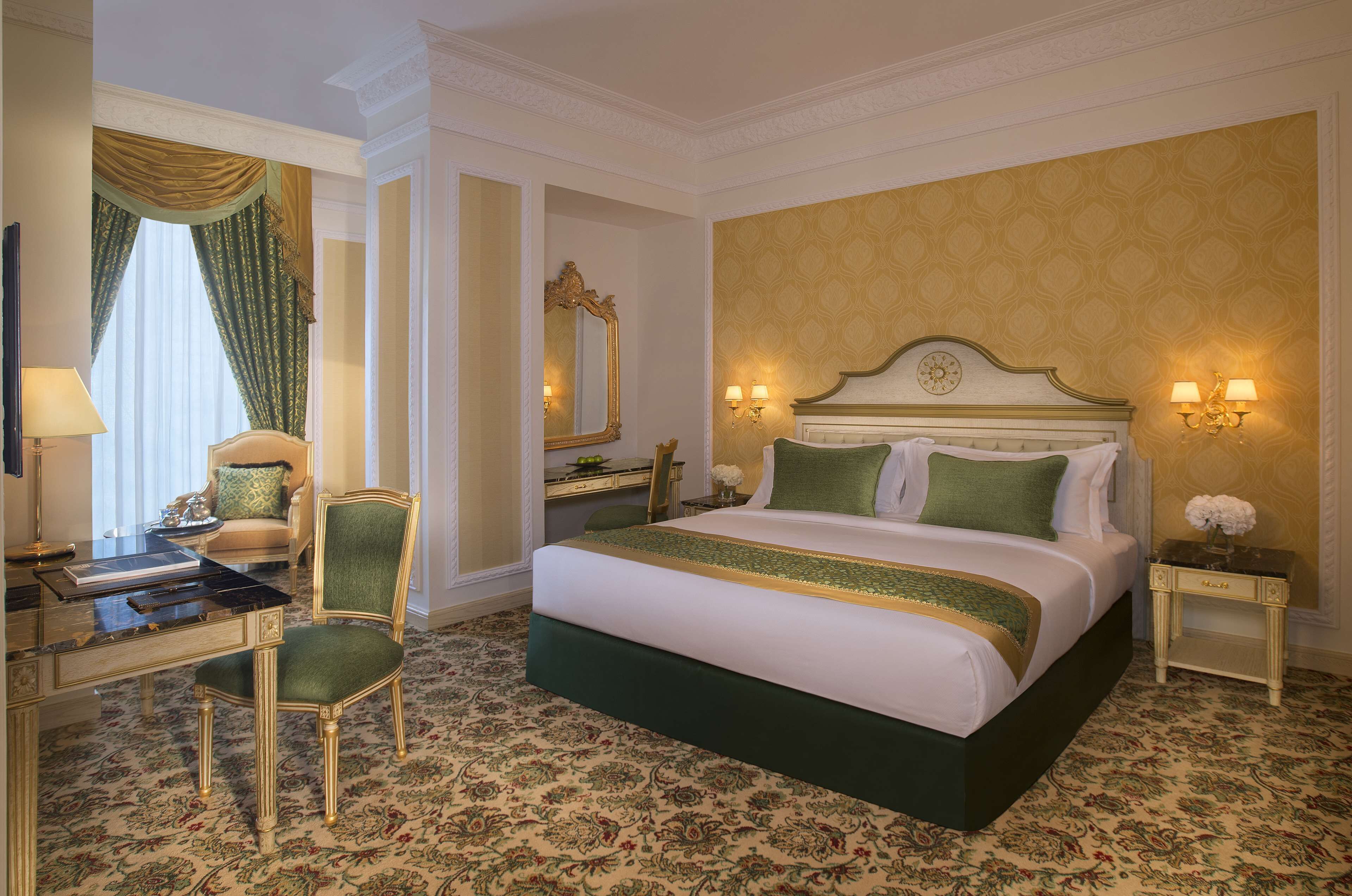 Una habitación de hotel con una cama grande, un escritorio con silla, un aparador y un espejo.