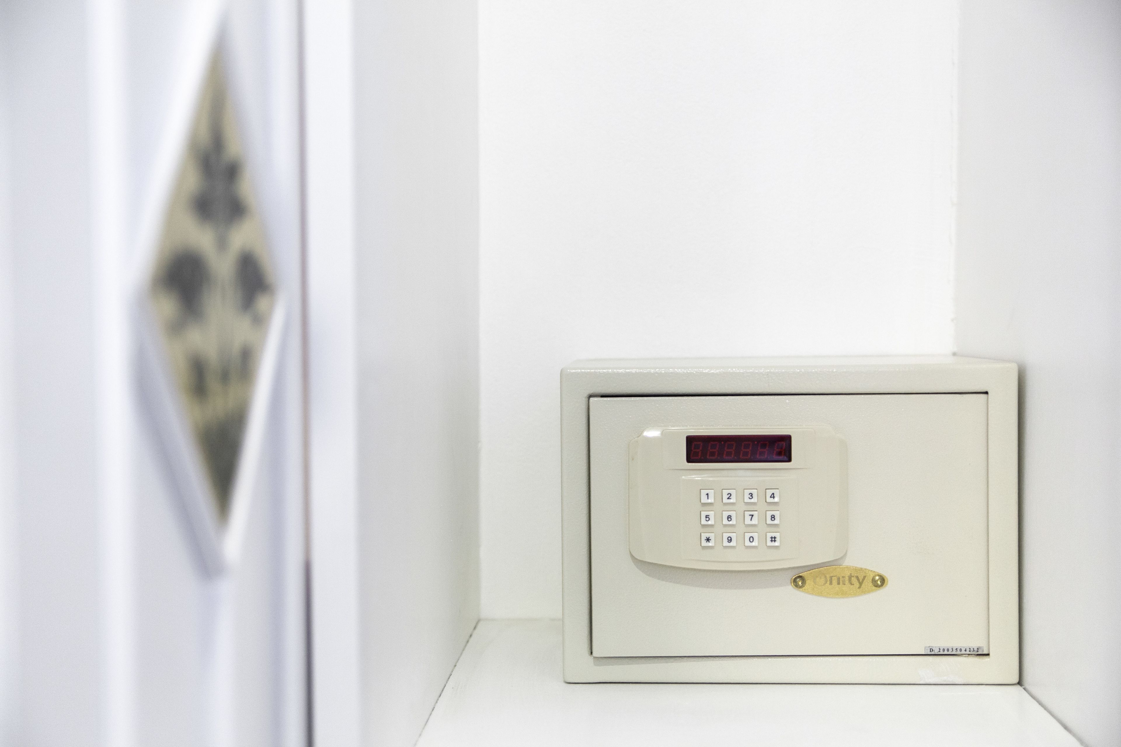 A white security keypad with a digital display, a keypad with numbers and symbols, and a brand name "Onity" on a white wall.