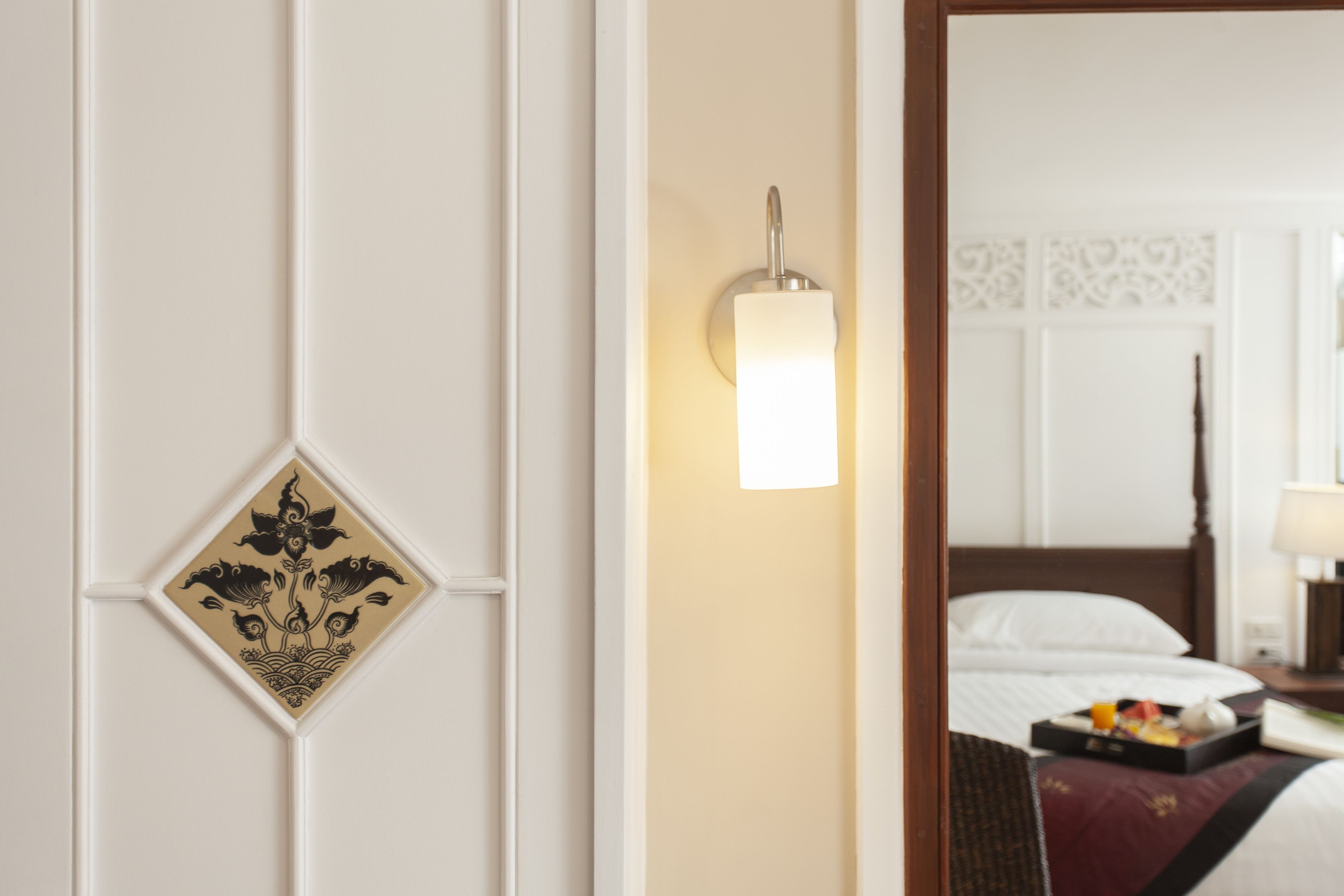 Une chambre d’hôtel avec un lit, une table de chevet et un luminaire fixé au mur.