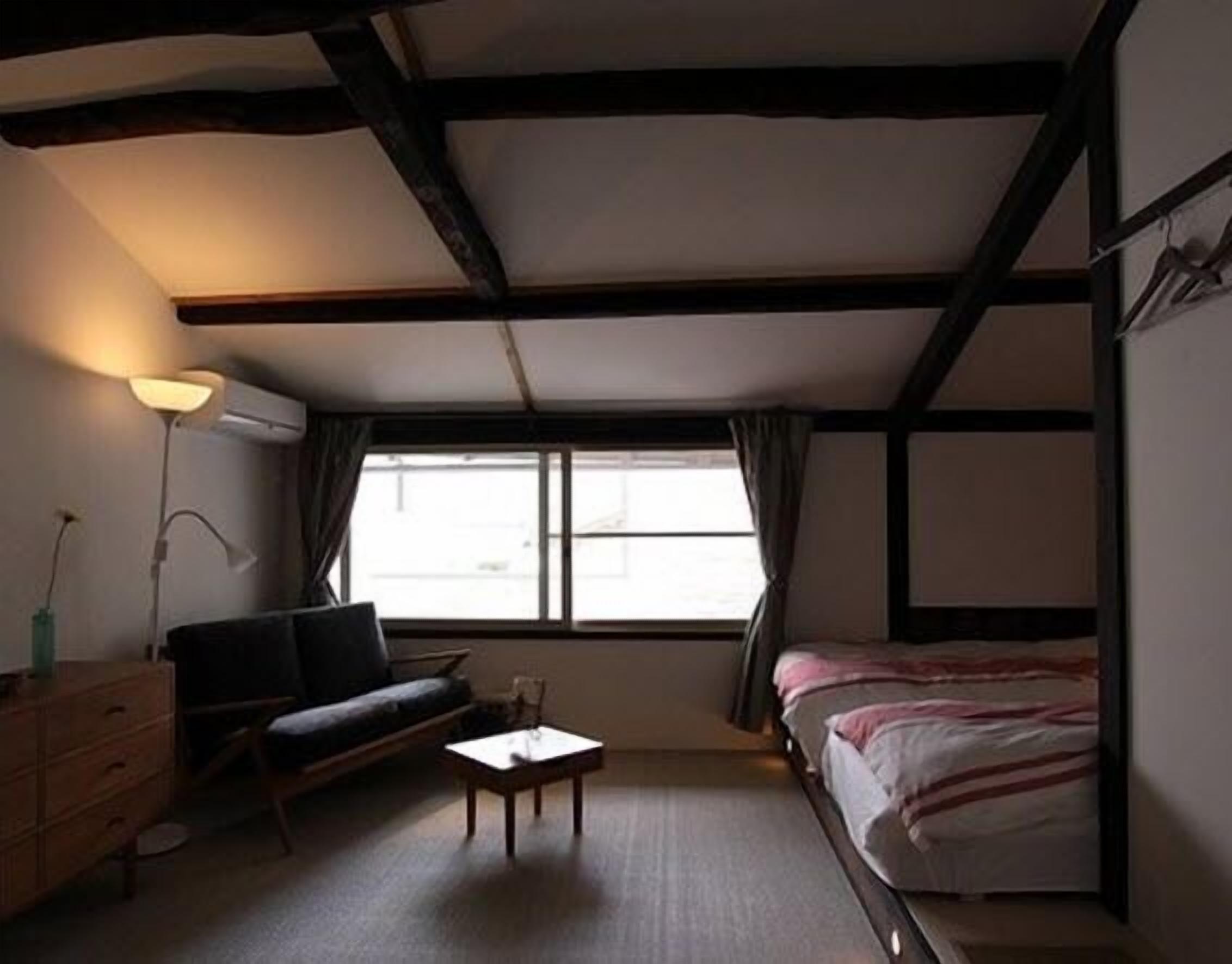 Una stanza con un letto, un divano, un tavolino e una lampada.