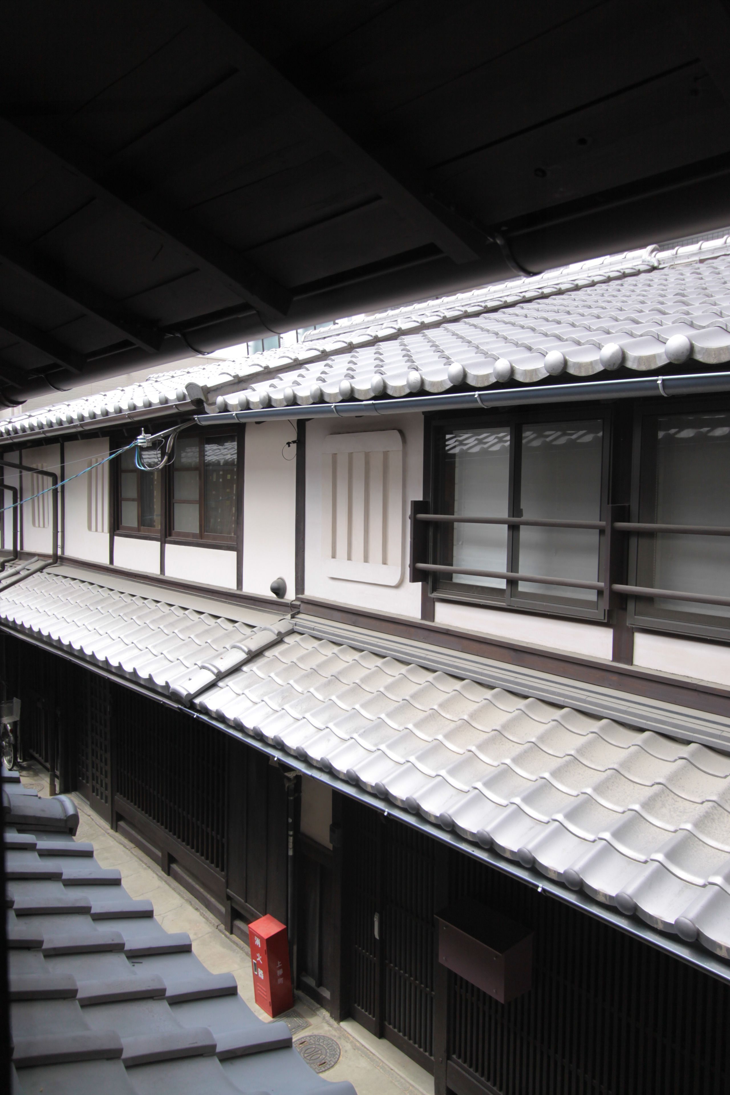 A traditional Japanese building with a tiled roof, wooden sliding doors, and a small red mailbox.