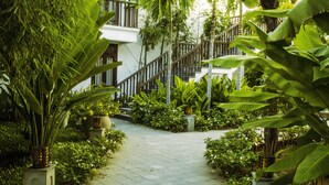 A pathway leading to a staircase surrounded by lush greenery and potted plants. - Legacy Hoi An Resort (Da Nang)