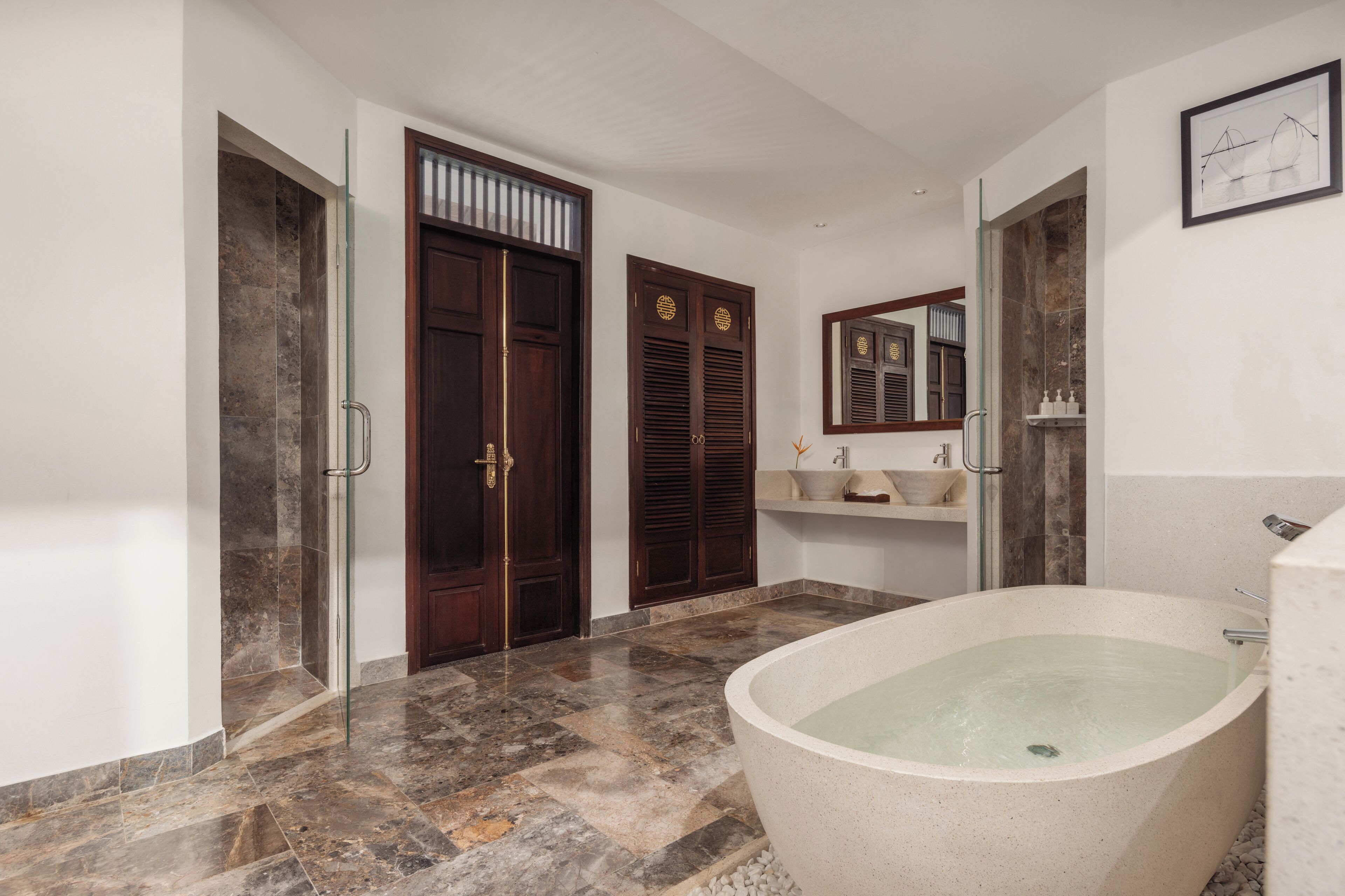 Un baño con una bañera independiente, un espejo grande y un tocador con lavabo y toallero.