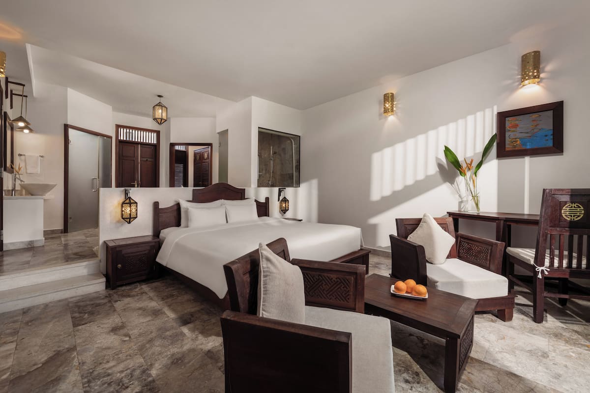 A modern hotel room with a large bed, wooden furniture, and a marble floor.