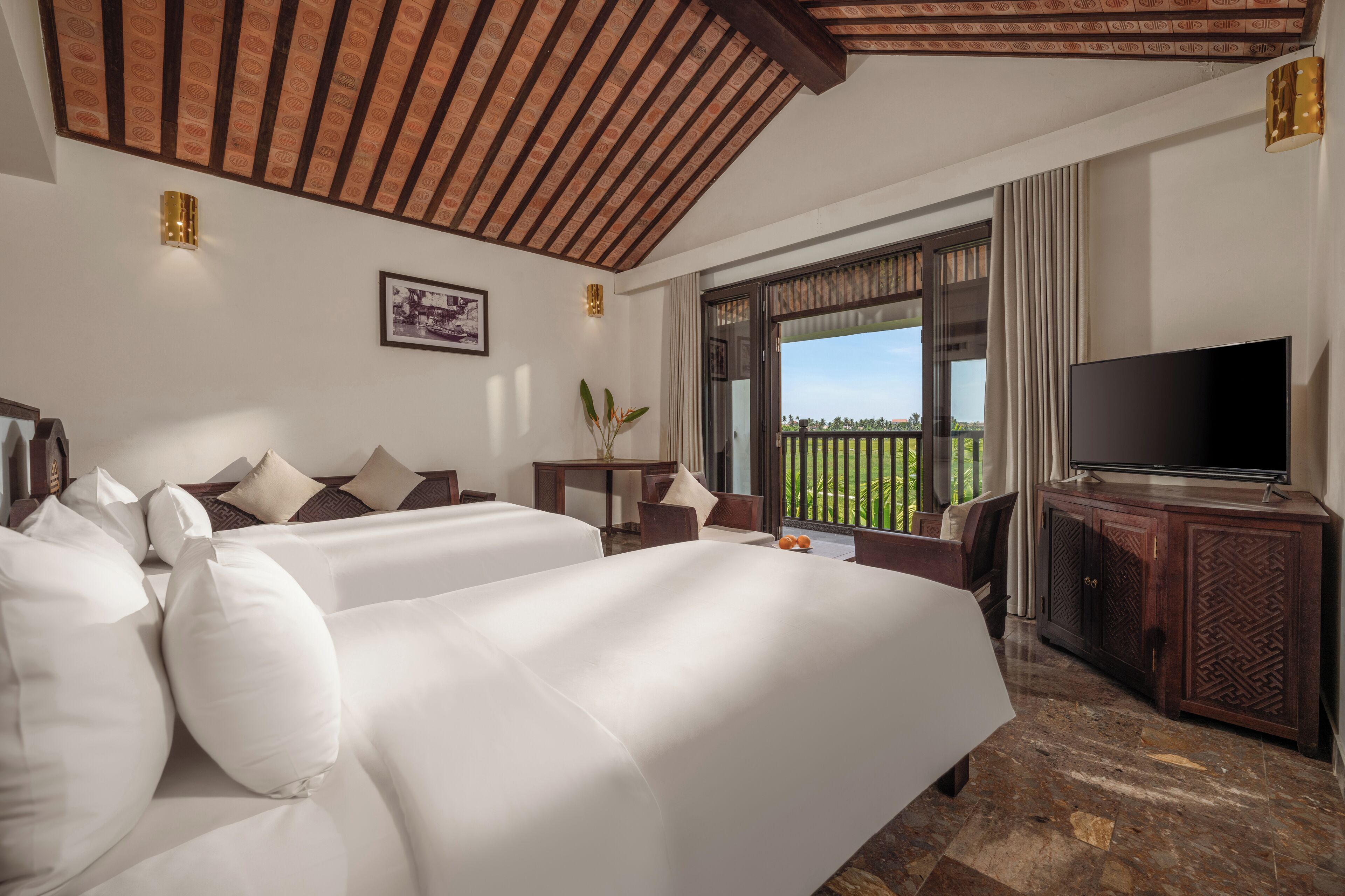 Een hotelkamer met twee tweepersoonsbedden, een televisie, een bureau en uitzicht op het omliggende landschap.