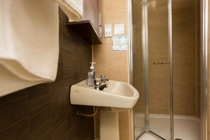 A bathroom with a sink, a shower, and a towel hanging on the wall.