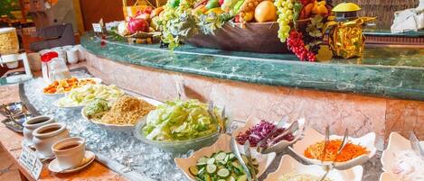 Un bufé con diversos alimentos y una presentación de frutas.