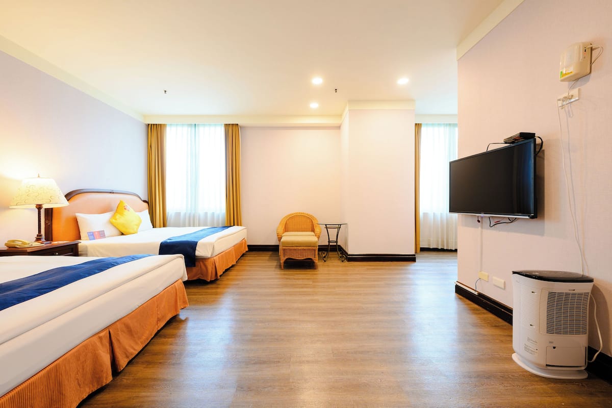 Ein Hotelzimmer mit zwei Betten, einem Fernseher, einem Sessel und einem Heizkörper.