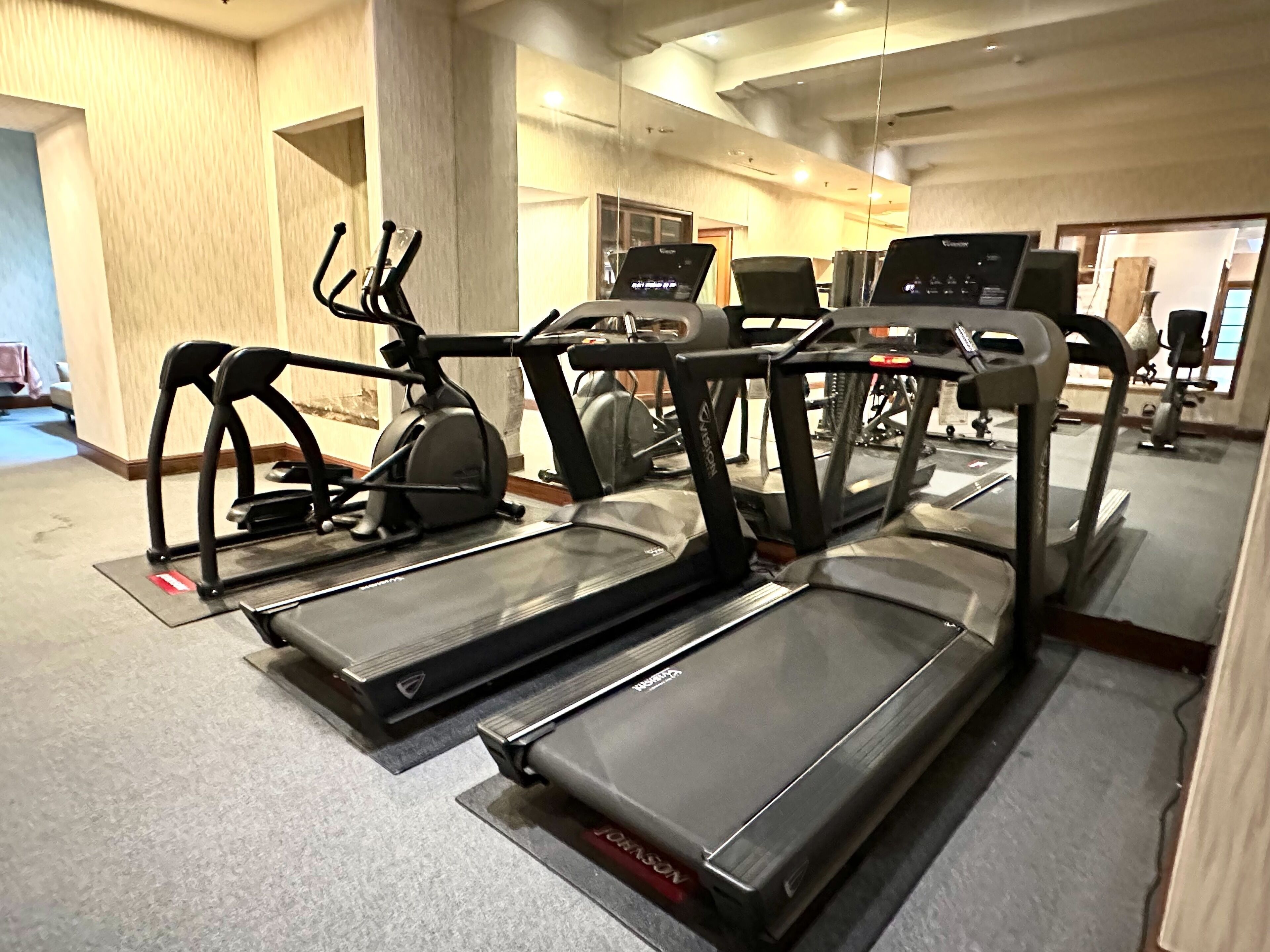 Une salle de sport équipée de plusieurs tapis de course et d’appareils d’exercice.