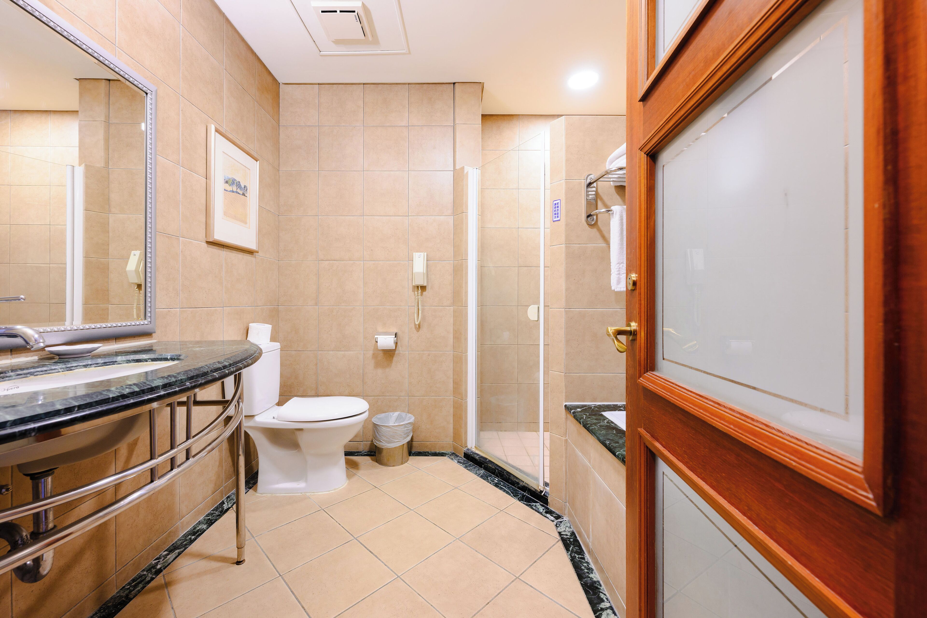 A bathroom with a marble sink, toilet, and a shower area.