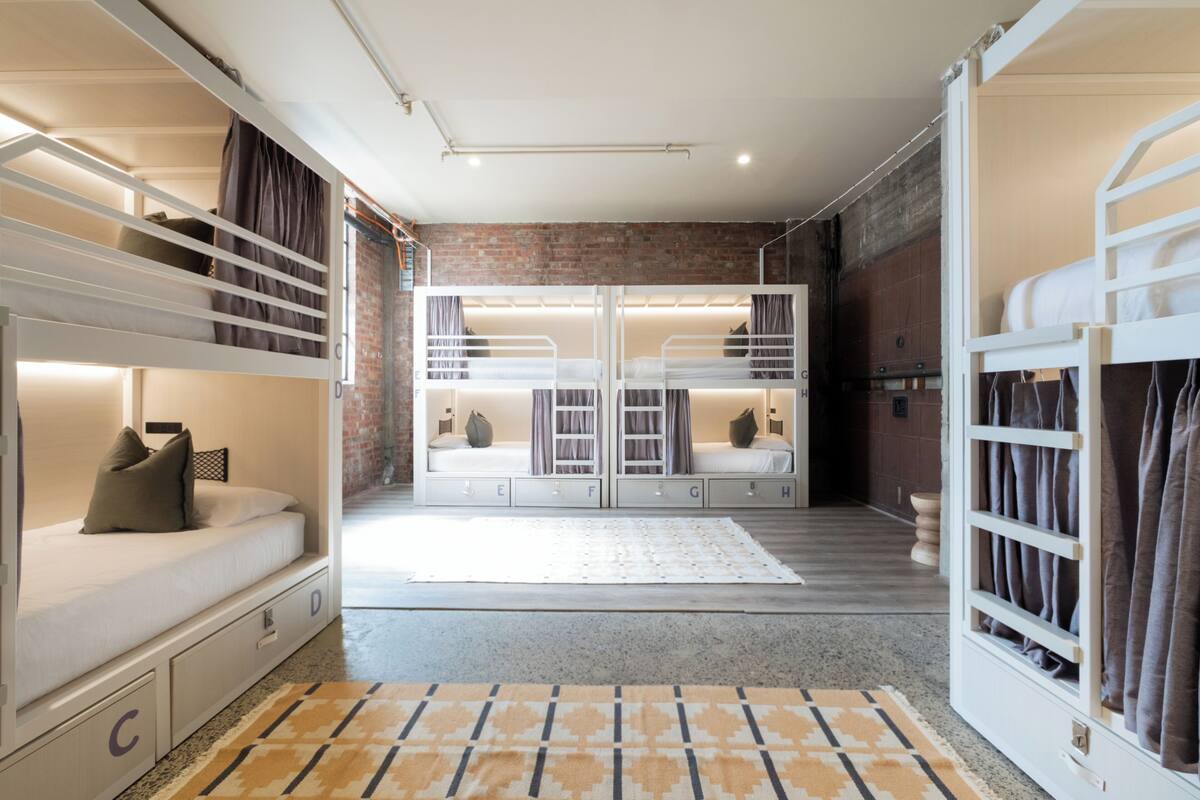 A modern room with bunk beds, a large mirror, and a brick wall.