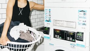 Una persona sosteniendo una cesta de ropa en un cuarto de lavado con lavadora y secadora apiladas.