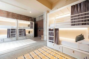 A hotel room with bunk beds, a brick wall, and a white door. - Little Drifter Melbourne (Melbourne)