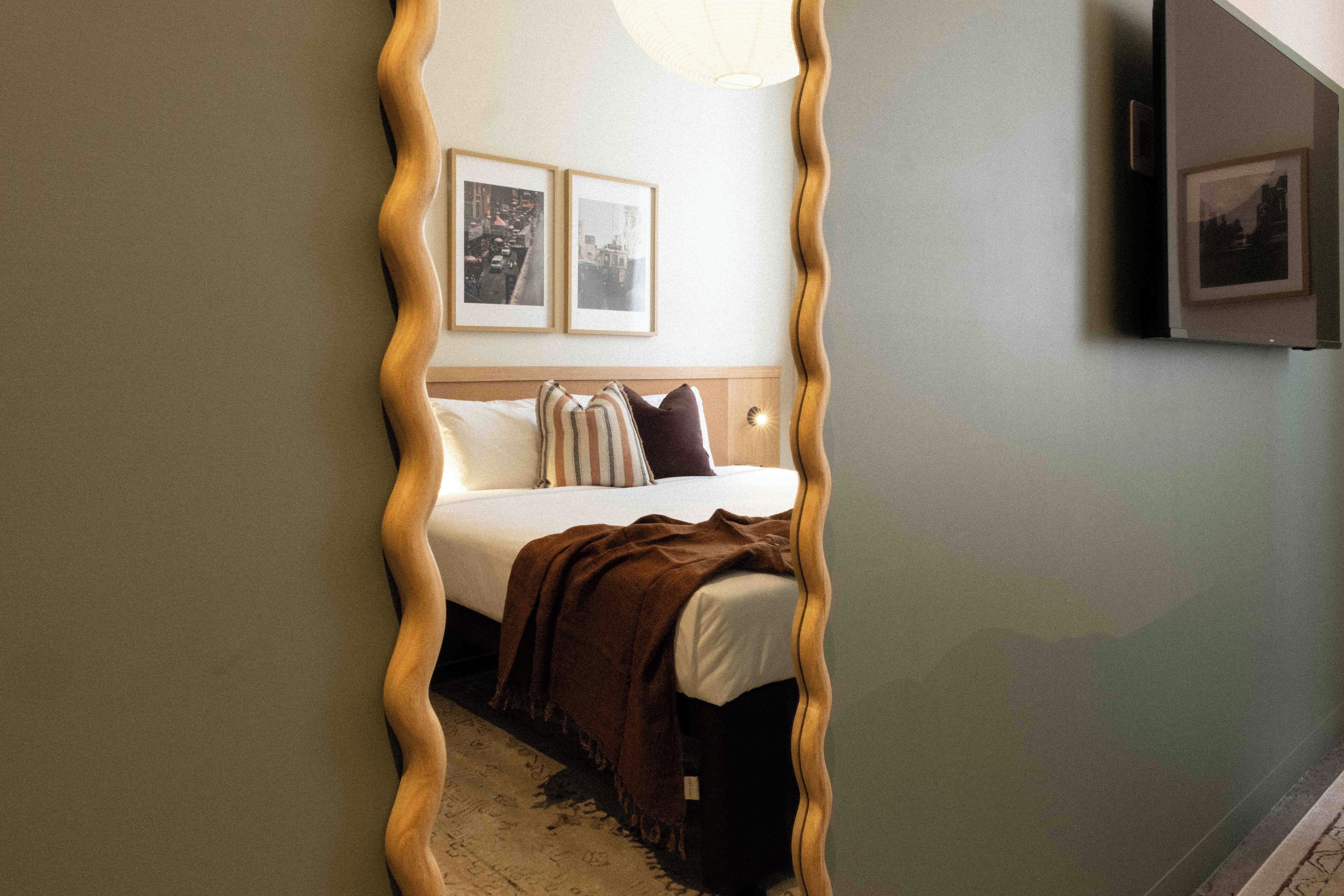 A bedroom with a bed, pillows, a blanket, and two framed pictures on the wall.