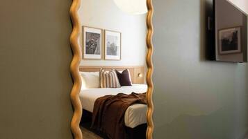 A bedroom with a bed, pillows, a blanket, and two framed pictures on the wall.