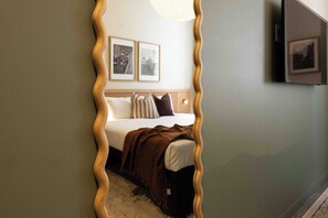 Une chambre à coucher avec un lit, des oreillers, une couverture et deux tableaux encadrés accrochés au mur.