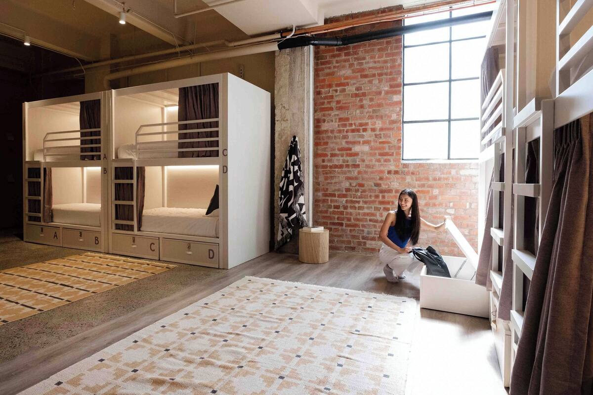 A modern room with bunk beds, a large window, and a brick wall.