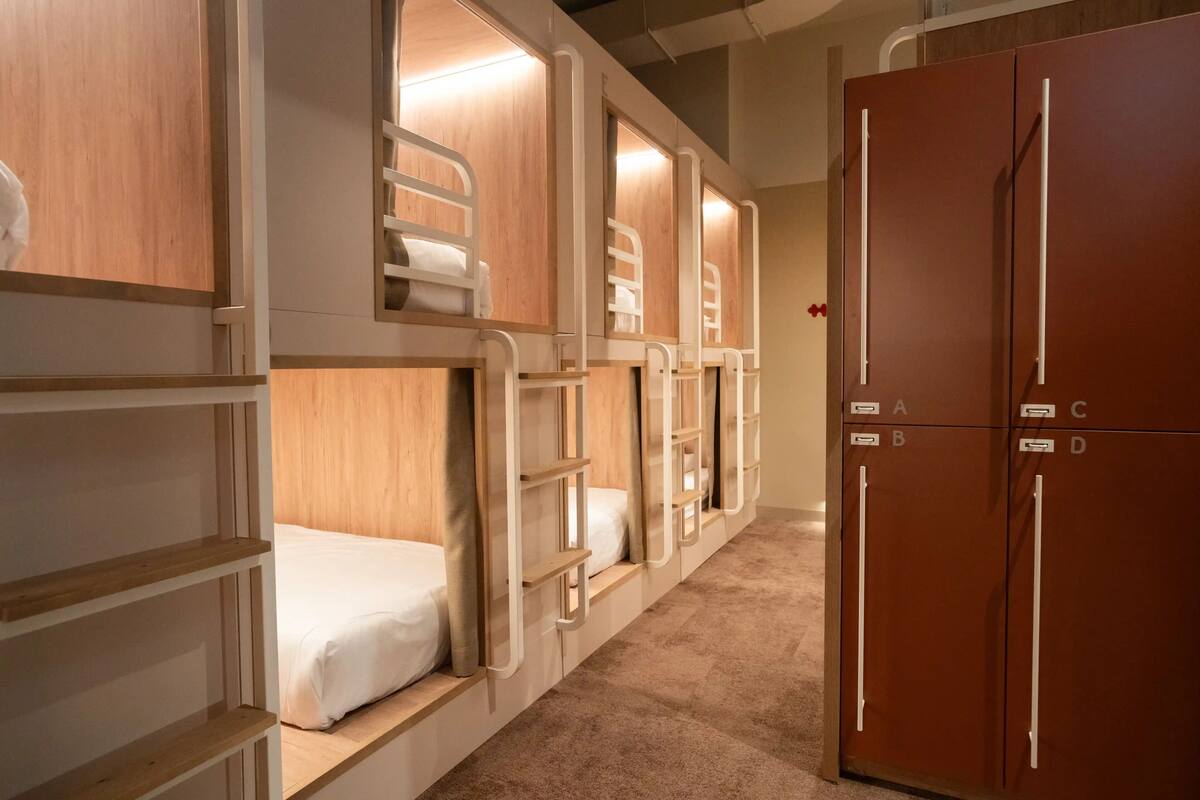 A hotel room with bunk beds, a wardrobe, and a carpeted floor.