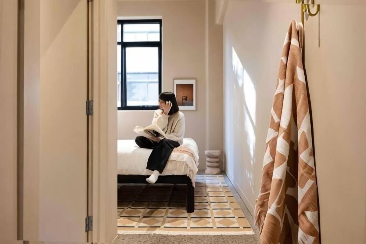 A room with a bed, a window, a door, and a patterned floor.