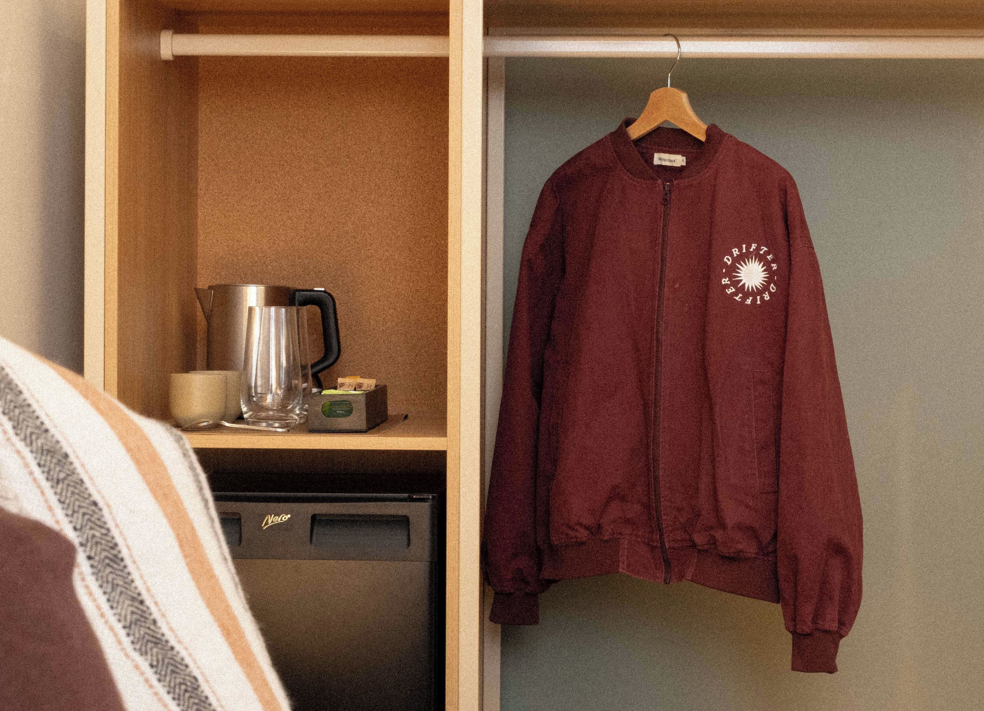 Een kamer met een hangende jas, een koffiezetapparaat en een klein apparaat op het aanrecht.