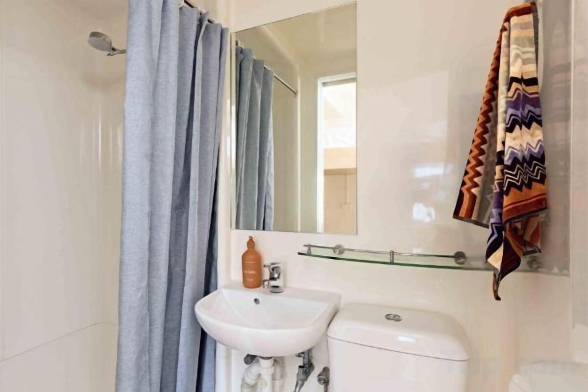A bathroom with a white sink, mirror, and toilet.