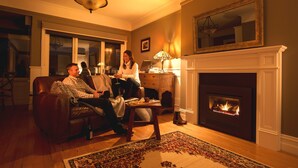 A living room with a fireplace, a sofa, a coffee table, and a lamp. - Marysville Garden Cottages (Marysville)