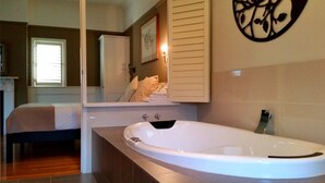A modern bathroom with a large bathtub, a mirror, and a towel rack. - Marysville Garden Cottages (Marysville)