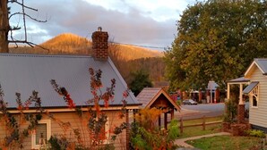 A rustic house with a metal roof, surrounded by a garden with a winding path and a wooden fence. - Marysville Garden Cottages (Marysville)