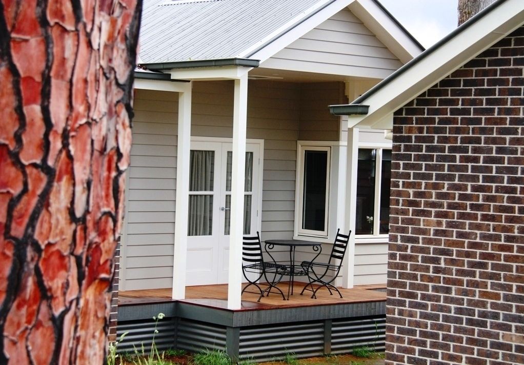 A covered patio with a table and chairs, a brick wall, and a white door.