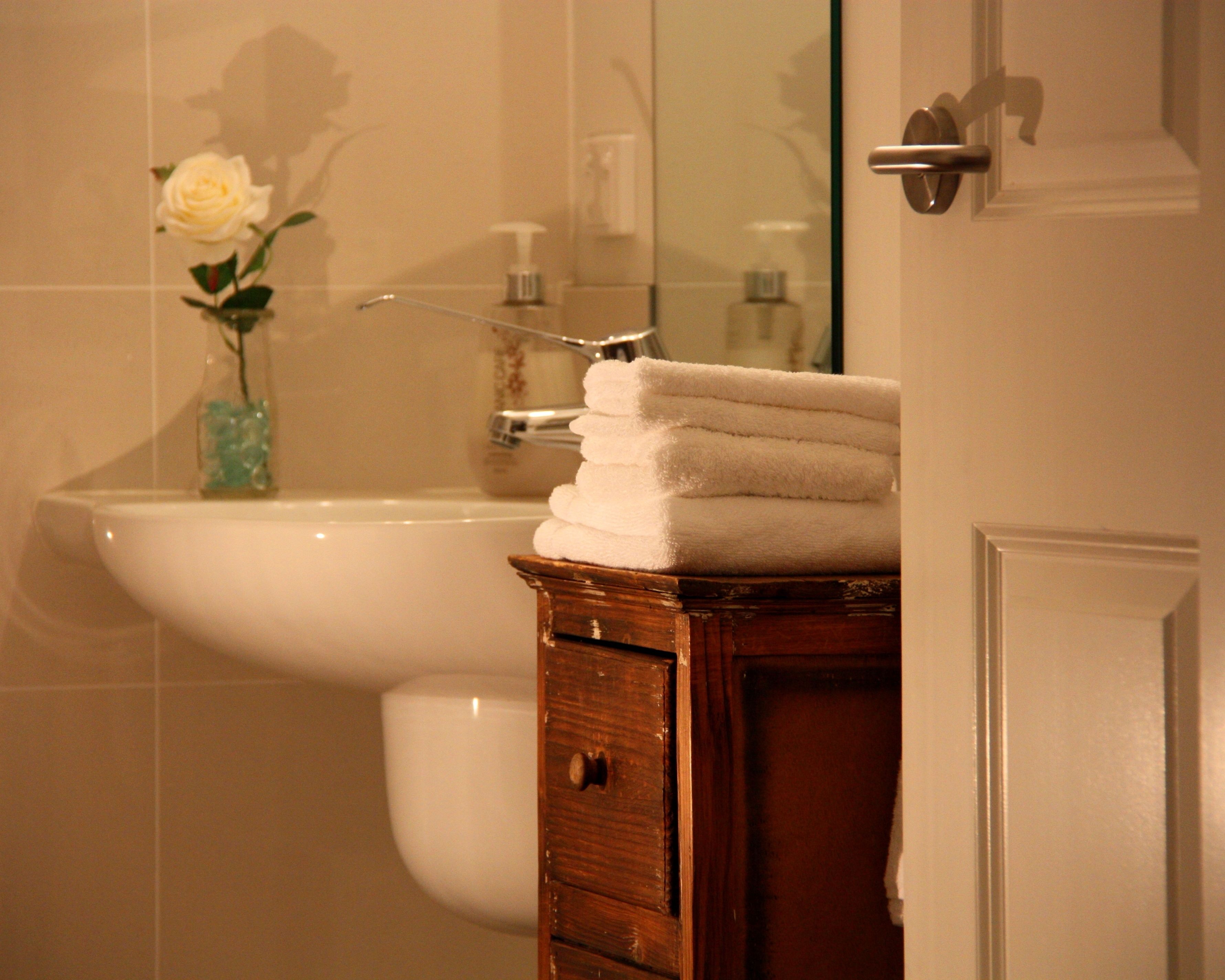 A bathroom with a sink, a mirror, and a wooden cabinet with towels.