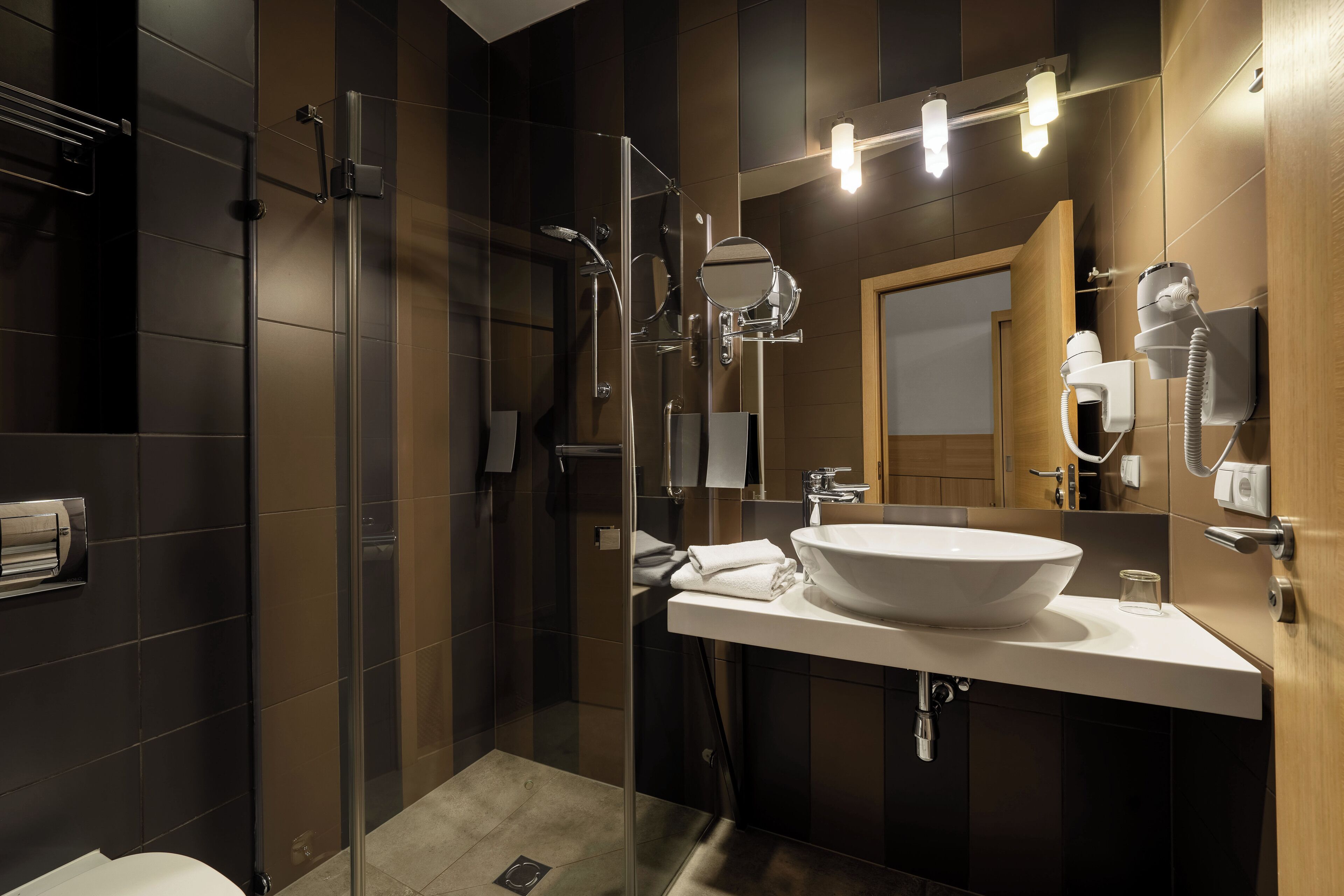 Un baño moderno con ducha de vidrio, un lavabo grande y un espejo con iluminación.
