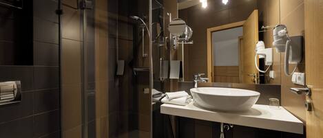 Un baño moderno con ducha de vidrio, un lavabo grande y un espejo con iluminación.