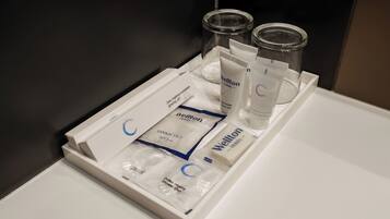 Bany d'hotel amb una safata que conté productes de tocador, com ara un estel·lo de dents, pasta de dents i gel de dutxa.