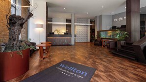 Un moderno vestíbulo de hotel con mostrador de recepción, zona de estar y una escalera.